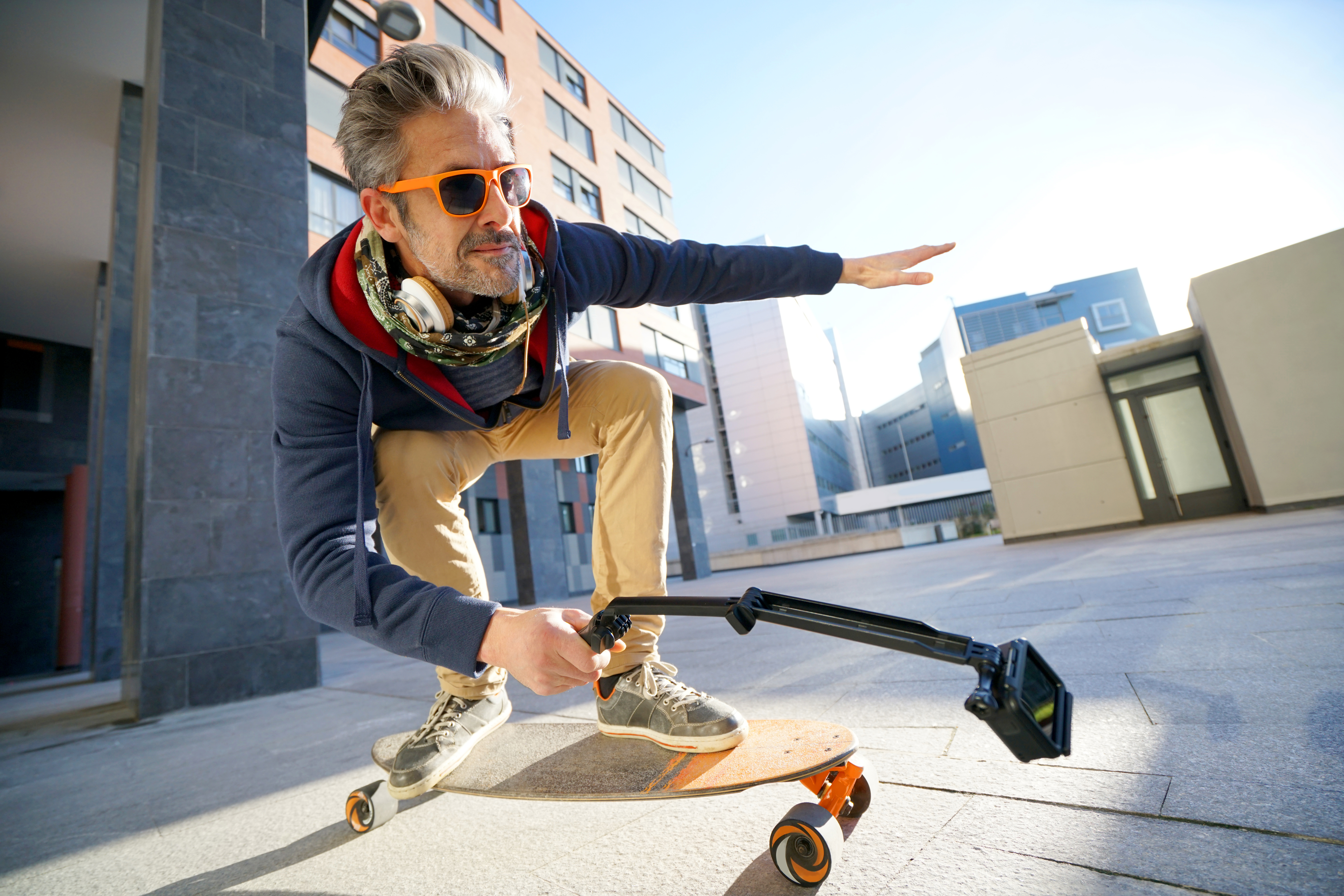 Mature man skateboarding in urban environment, filming himself